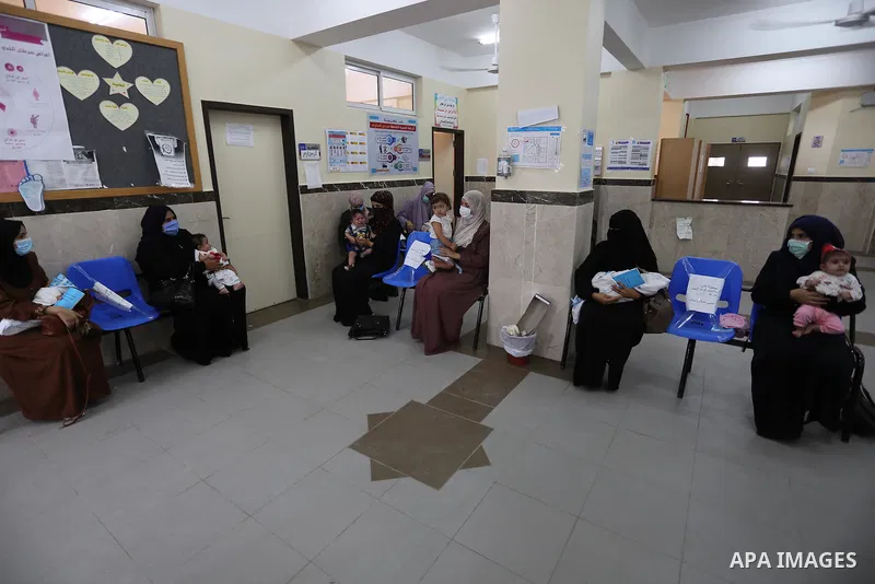 Palestinian women mask-clad due to the Covid-19 coronavirus pandemic wait with their children in a UN clinic to take Polio vaccine and Rota virus vaccines, in Deir Al-Balah, in the center of the Gaza Strip, on Sept. 12,...