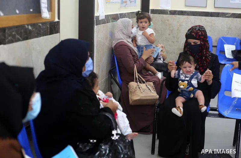 Palestinian women mask-clad due to the Covid-19 coronavirus pandemic wait with their children in a UN clinic to take Polio vaccine and Rota virus vaccines, in Deir Al-Balah, in the center of the Gaza Strip, on Sept. 12,...