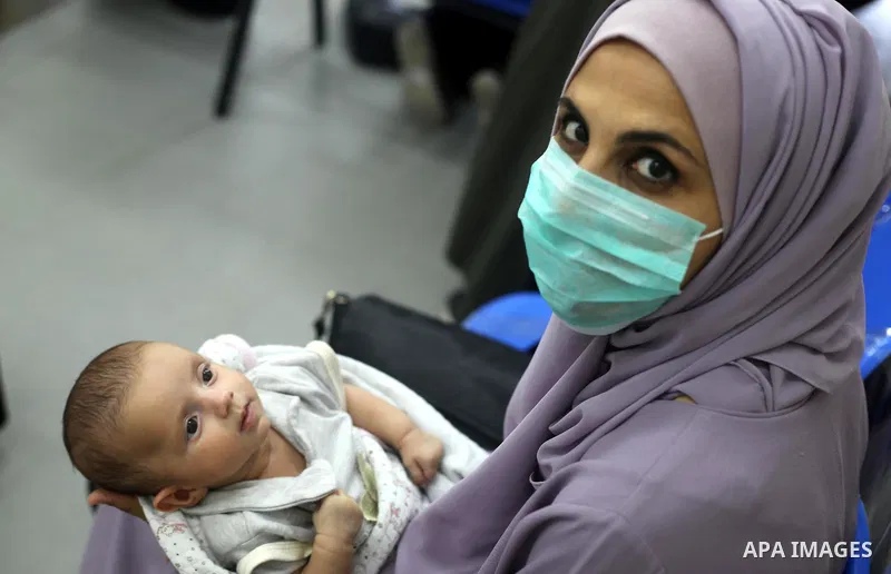 Palestinian women mask-clad due to the Covid-19 coronavirus pandemic wait with their children in a UN clinic to take Polio vaccine and Rota virus vaccines, in Deir Al-Balah, in the center of the Gaza Strip, on Sept. 12,...