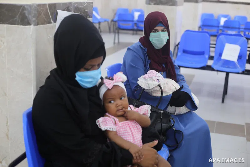 Palestinian women mask-clad due to the Covid-19 coronavirus pandemic wait with their children in a UN clinic to take Polio vaccine and Rota virus vaccines, in Deir Al-Balah, in the center of the Gaza Strip, on Sept. 12,...