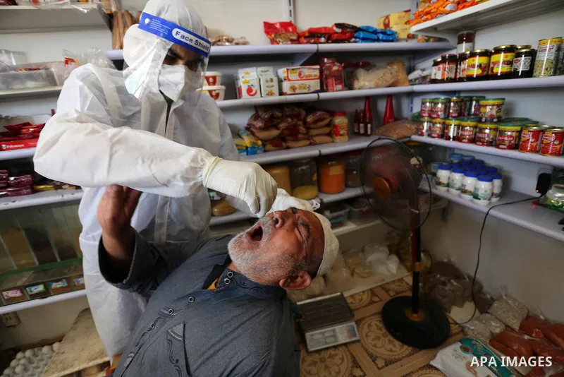 A Palestinian midical wearing protective gear, takes a swab sample from a man during a COVID-19 screening campaign in Deir Al-Balah, in the central Gaza Strip, on September 24, 2020. Photo by Ashraf Amra
