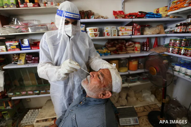 A Palestinian midical wearing protective gear, takes a swab sample from a man during a COVID-19 screening campaign in Deir Al-Balah, in the central Gaza Strip, on September 24, 2020. Photo by Ashraf Amra
