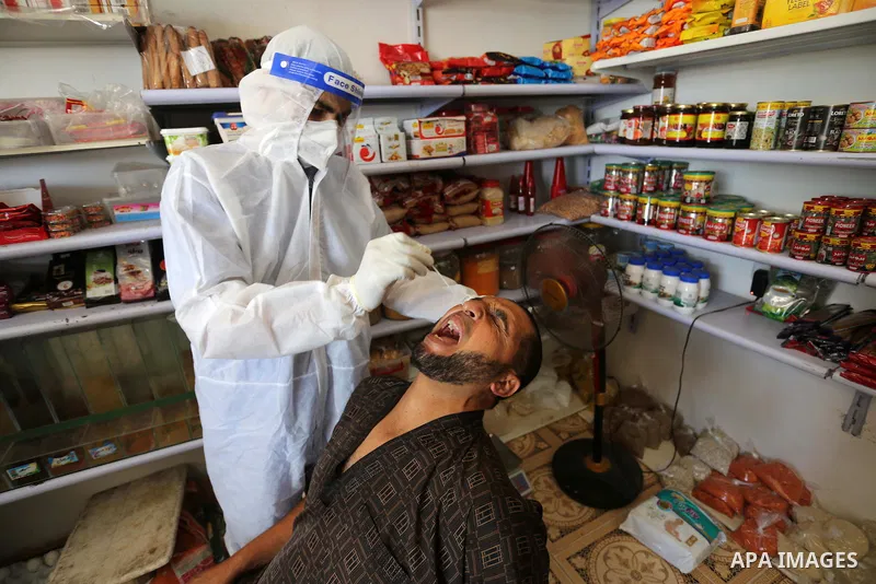 A Palestinian midical wearing protective gear, takes a swab sample from a man during a COVID-19 screening campaign in Deir Al-Balah, in the central Gaza Strip, on September 24, 2020. Photo by Ashraf Amra