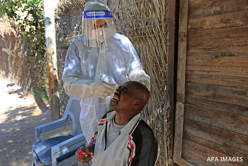 A Palestinian midical wearing protective gear, takes a swab sample from a man during a COVID-19 screening campaign in Deir Al-Balah, in the central Gaza Strip, on September 24, 2020. Photo by Ashraf Amra
