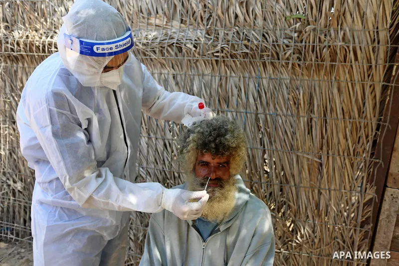 A Palestinian midical wearing protective gear, takes a swab sample from a man during a COVID-19 screening campaign in Deir Al-Balah, in the central Gaza Strip, on September 24, 2020. Photo by Ashraf Amra