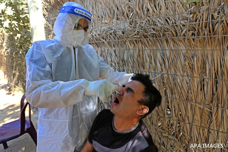 A Palestinian midical wearing protective gear, takes a swab sample from a man during a COVID-19 screening campaign in Deir Al-Balah, in the central Gaza Strip, on September 24, 2020. Photo by Ashraf Amra