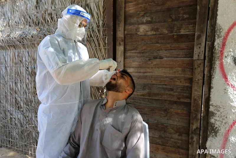 A Palestinian midical wearing protective gear, takes a swab sample from a man during a COVID-19 screening campaign in Deir Al-Balah, in the central Gaza Strip, on September 24, 2020. Photo by Ashraf Amra
