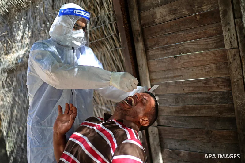 A Palestinian midical wearing protective gear, takes a swab sample from a man during a COVID-19 screening campaign in Deir Al-Balah, in the central Gaza Strip, on September 24, 2020. Photo by Ashraf Amra