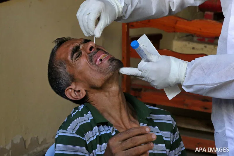 A Palestinian midical wearing protective gear, takes a swab sample from a man during a COVID-19 screening campaign in Deir Al-Balah, in the central Gaza Strip, on September 24, 2020. Photo by Ashraf Amra