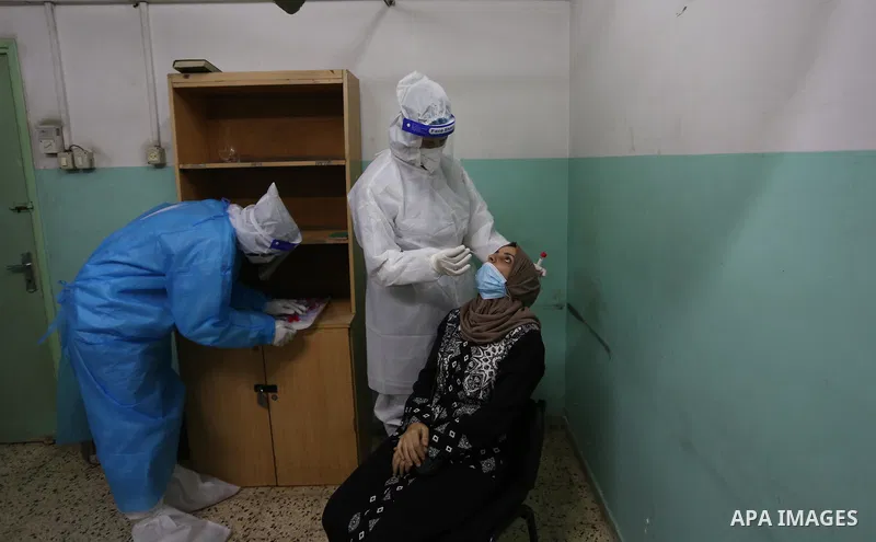 A Palestinian medical worker wearing protective gear, takes a swab sample COVID-19 screening, for travelers through the Rafah crossing after a decision to reopen it in the coming days at a health center, in Nuseirat in t...