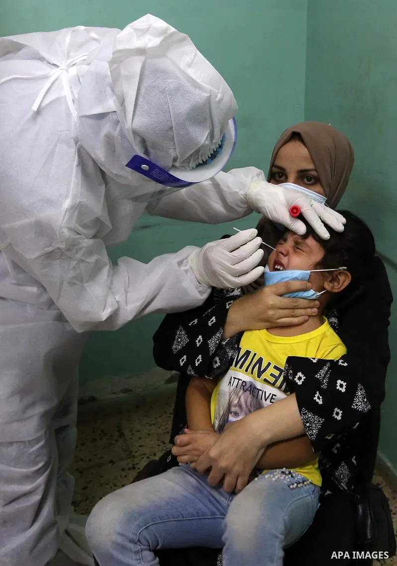 A Palestinian medical worker wearing protective gear, takes a swab sample COVID-19 screening, for travelers through the Rafah crossing after a decision to reopen it in the coming days at a health center, in Nuseirat in t...