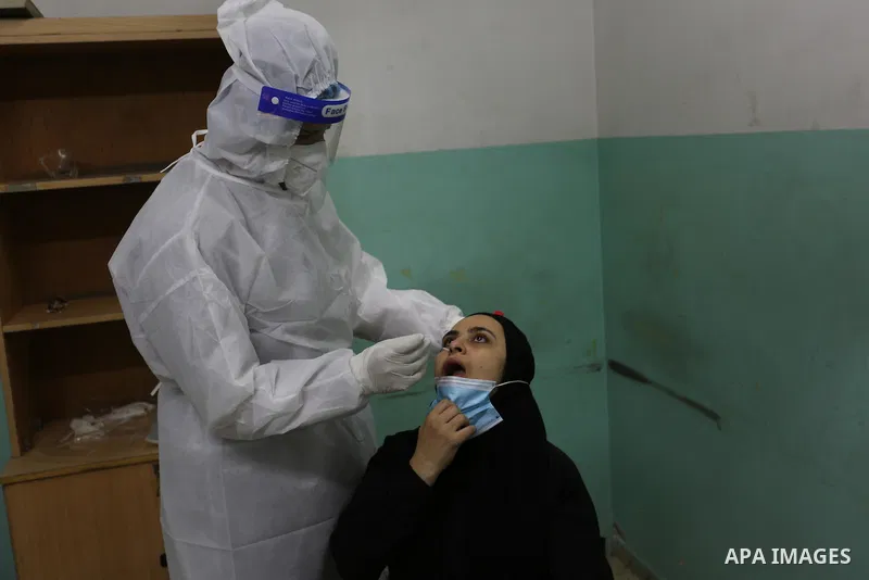 A Palestinian medical worker wearing protective gear, takes a swab sample COVID-19 screening, for travelers through the Rafah crossing after a decision to reopen it in the coming days at a health center, in Nuseirat in t...