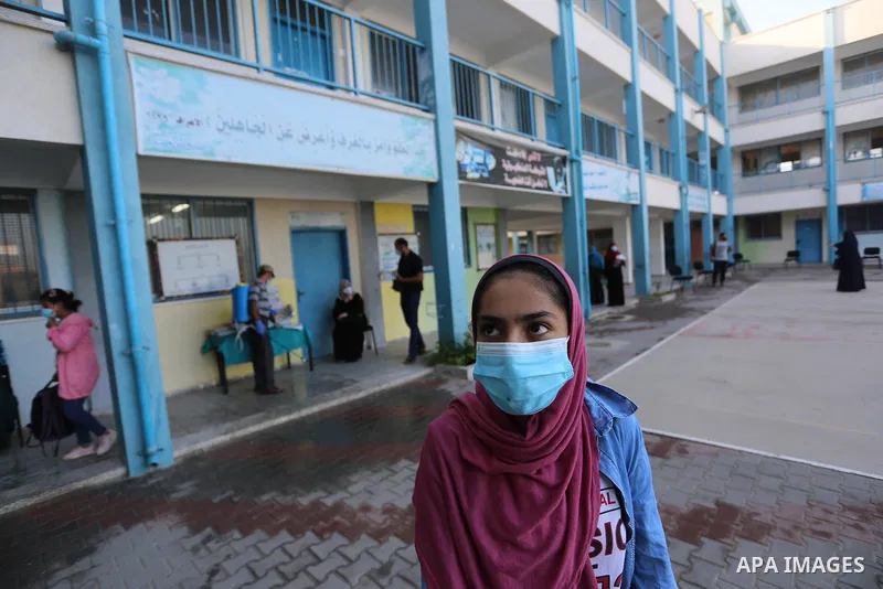 Palestinian students wearing protective masks, as they receive textbooks one of the United Nations Relief and Works Agency (UNRWA) schools, amid the coronavirus disease (COVID-19), at their school in Dair Al Balah in the...