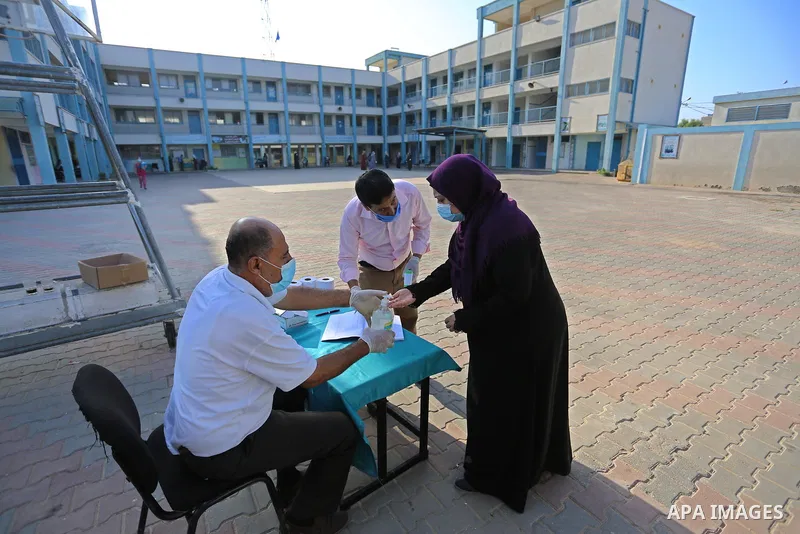 Palestinians wearing protective masks are tested for body temperature while they are entering one of the United Nations Relief and Works Agency (UNRWA) schools, amid the coronavirus disease (COVID-19), at their school in...