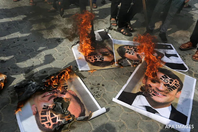 Palestinian Hamas supporters burn pictures depicting French President Emmanuel Macron during a protest against the publications of a cartoon of Prophet Mohammad in France and Macron's comments, in Khan Younis in the sout...