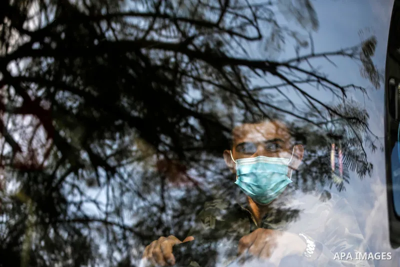 A Palestinian man, wearing a mask due to the COVID-19 coronavirus pandemic, sits behind the window of a bus in Gaza City on November 8, 2020. Photo by Osama Baba