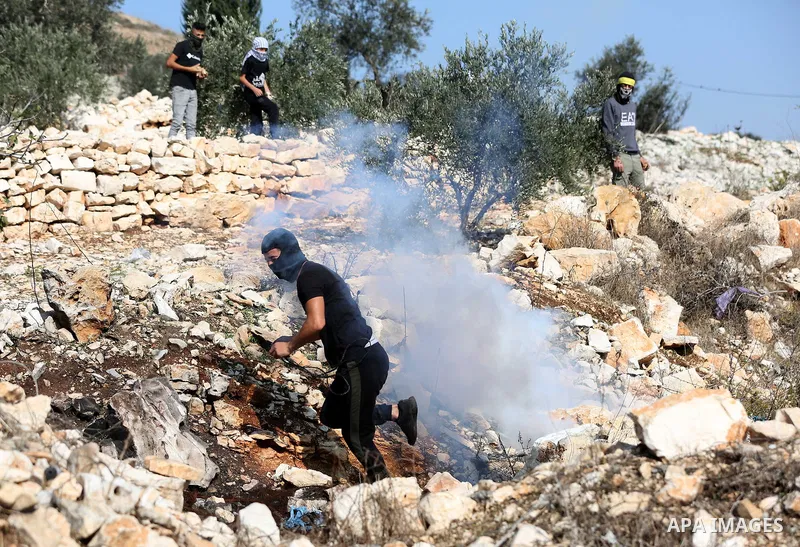 A Palestinian protester returns throwing a tear gas canister during clashes following a weekly demonstration against the expropriation of Palestinian land by Israel in the village of Kfar Qaddum, near the West Bank city...