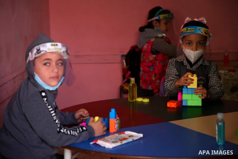 Palestinian children, clad in masks and face-shields due to the COVID-19 coronavirus pandemic, play inside their kindergarten, in Gaza City on November 23, 2020. Photo by Mahmoud Ajjour
