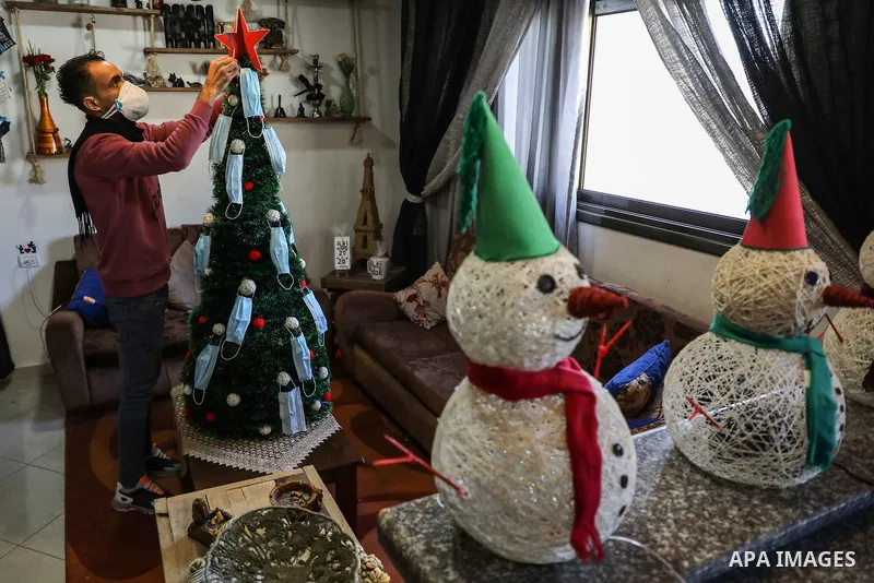 Palestinian artist Wissam Farhat decorates a Christmas tree with protective masks amid the COVID-19 pandemic in Gaza City on December 20, 2020. A Christmas tree is a decorated tree, usually an evergreen conifer, such as...