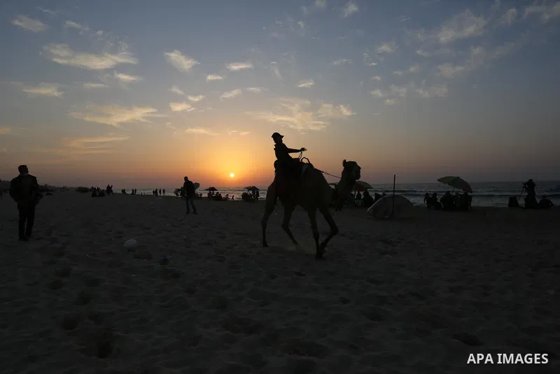 A Palestinian man rides a camel at a beach during sunset in the last day of 2020, before the complete closure amid the spread of the Coronavirus COVID-19, in Gaza City on December 31, 2020, in the fourth week after the M...