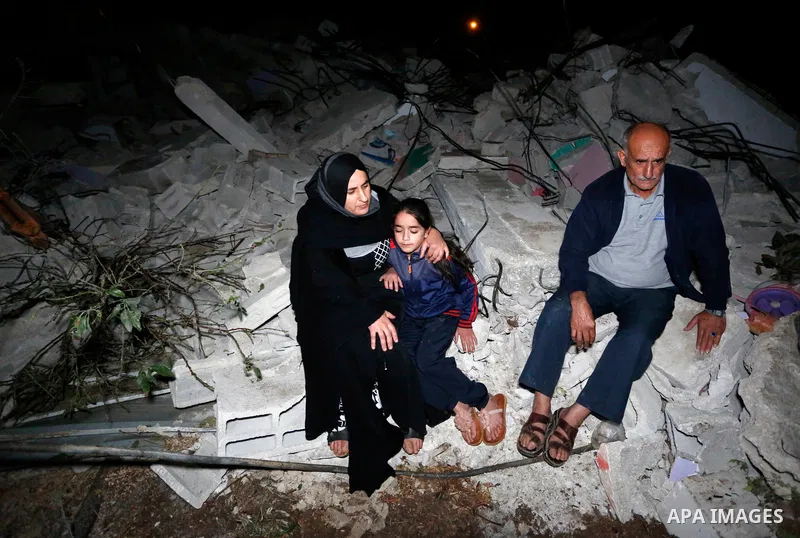 Palestinians sit over the rubble of a house demolished by the Israeli army in the West Bank city of Nanlus, November 2, 2020. The Israeli military says it has demolished the house of prisoner Khalil Dweikat who carried o...