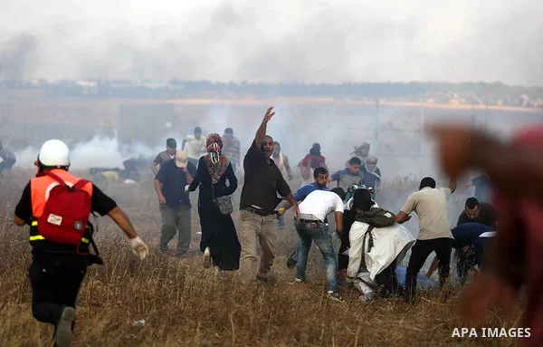 Palestinian protesters run for cover from tear gas canisters fired by Israeli security forces during clashes in a tent city protest where Palestinians demand the right to return to their homeland and against U.S. embassy...
