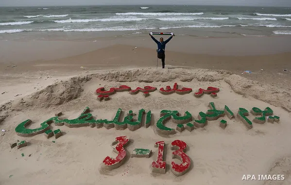 A Palestinian artist Mohammed Totah with amputated leg poses for a picture behind a sand sculpture to mark the Palestinian Wounded's Day in Gaza City, on March 12, 2017. Photo by Ashraf Amra