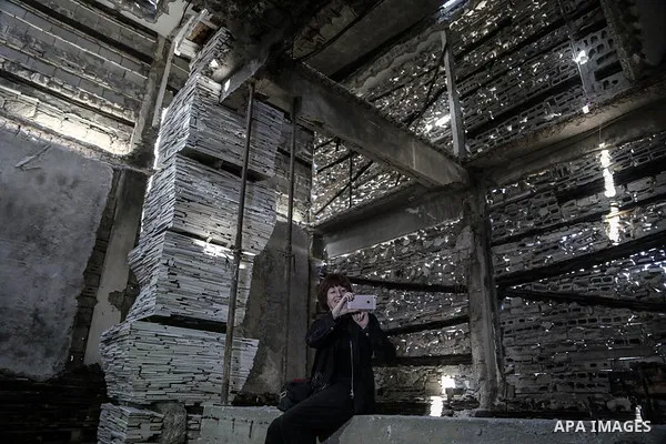 Dutch artist Marjan Teeuwen uses her phone to take a photo for architectural work that involves re-assembling wreckage of a house, that was destroyed during 2014, and turning it into artistic structures, in Khan Younis i...