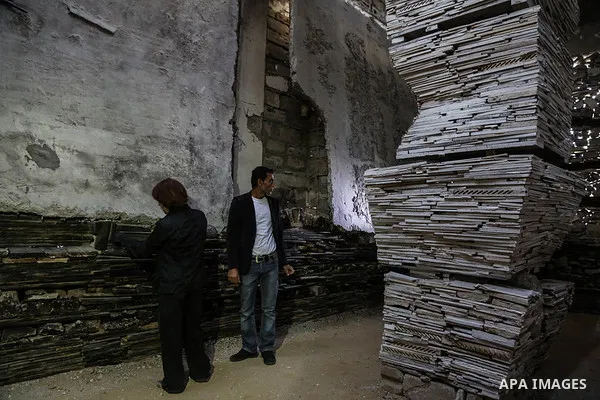 Dutch artist Marjan Teeuwen speaks with her assistant as she creates an architectural work that involves re-assembling wreckage of a house, that was destroyed during 2014, and turning it into artistic structures, in Khan...