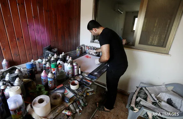 A Palestinian artist Khaled Salama, 27, paints on glass pots using colored sand, at his work shop in the West Bank city of Salfit, on Sep. 27, 2016. Photo by Shadi Hatem