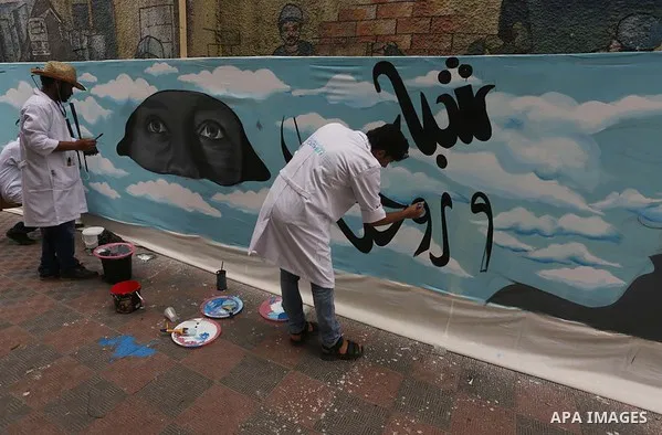 Palestinian artists draw a mural on the wall to mark the International Youth Day, in Gaza city, on Sep. 09, 2015. Photo by Mohammed Asad