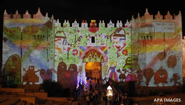 People watch an audiovisual light show projected over the ancient walls of Jerusalem's Damascus Gate in the old city during the Festival of Lights, on June 4, 2015. The festival is an annual event where thousands take pa...