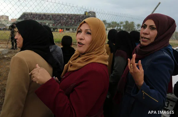 Palestinian women watch the football match between Al-Nuseirat and Al-Jalaa standing outside the fence of the stadium, at Nuseirat refugee camp, in the central of Gaza Strip, on January 28, 2018. Palestinian police allow...