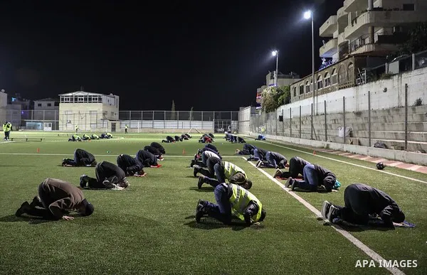 Palestinian Muslims some wearing masks as a precaution against the spread of the coronavirus disease (COVID-19) perform a night prayer known as ''Tarawih'' on the of a football stadium after the mosques are closed after...