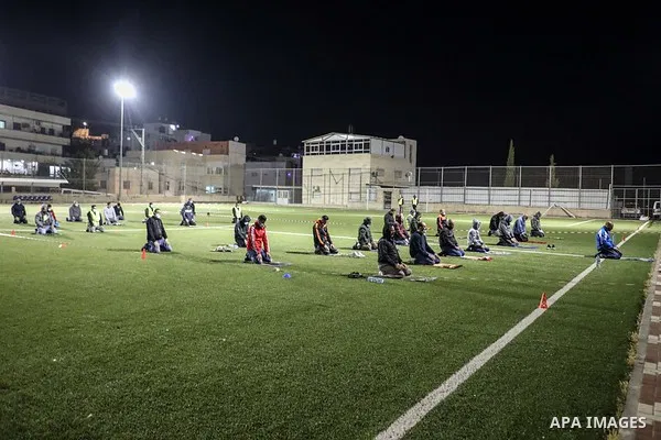 Palestinian Muslims some wearing masks as a precaution against the spread of the coronavirus disease (COVID-19) perform a night prayer known as ''Tarawih'' on the of a football stadium after the mosques are closed after...