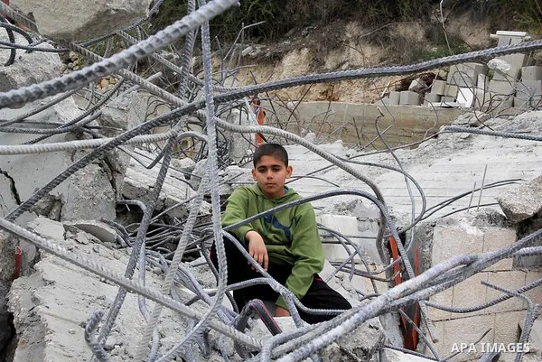 A Palestinian boy stands on the rubble of his family house that was demolished by Jerusalem municipality workers in Jerusalem on Jan. 07, 2016. Israeli police Thursday demolished two Palestinian-owned homes in Ein el-Law...