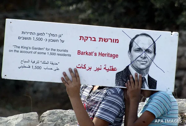 Palestinian boys hold a poster of Jerusalem mayor Nir Barkat with his face crossed out in the Silwan neighborhood of east Jerusalem on 29 October 2010. The sign refers to Barak's plan to disrupt 1,500 Palestinians in ord...