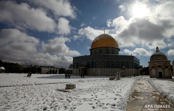 Palestinians walk in front of the Dome of the Rock mosque in Jerusalem's Old City following a snowstorm on December 13, 2013. The hilltop city of Jerusalem was paralysed today by its fiercest snowstorm in years, with its...