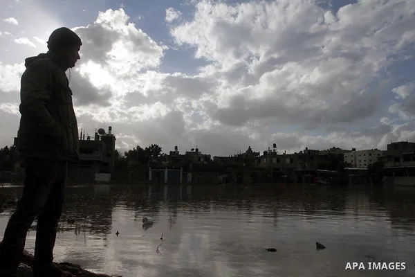 A Palestinian youth looks on a rains swamp following a downpour on a stormy day in north Gaza Strip, December 11, 2013. The Gaza Strip Power Authority is worried that electricity will be available for less than six hours...