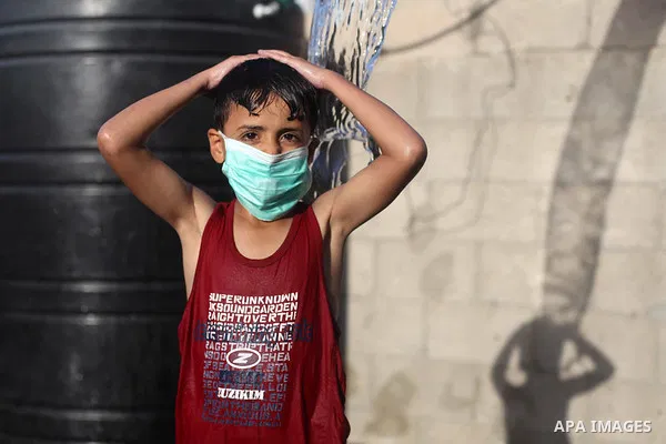 Palestinian children wear face masks play together as they cool off in the water in a metal frame pool erected on the rooftop of a residential building, amid the spread of the coronavirus pandemic, in Gaza City on Septem...