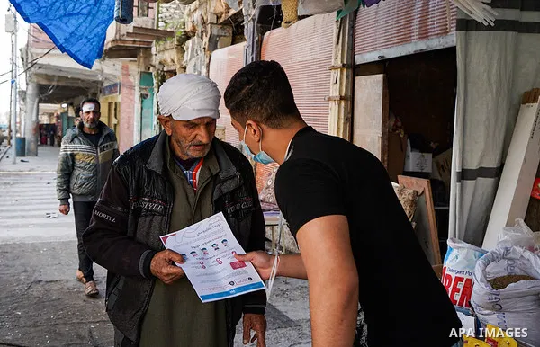 Iraqis look on the posters during awareness campaign about the coronavirus disease (COVID-19) in the northern Iraqi city of Mosul, on February 26. 2020. Photo by Ismail Adnan