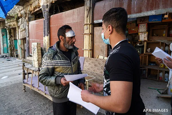 Iraqis look on the posters during awareness campaign about the coronavirus disease (COVID-19) in the northern Iraqi city of Mosul, on February 26. 2020. Photo by Ismail Adnan