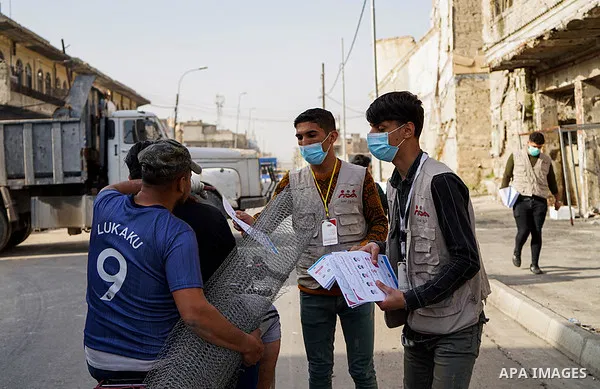 Iraqis look on the posters during awareness campaign about the coronavirus disease (COVID-19) in the northern Iraqi city of Mosul, on February 26. 2020. Photo by Ismail Adnan