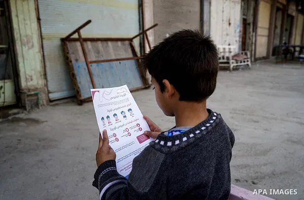 Iraqis look on the posters during awareness campaign about the coronavirus disease (COVID-19) in the northern Iraqi city of Mosul, on February 26. 2020. Photo by Ismail Adnan