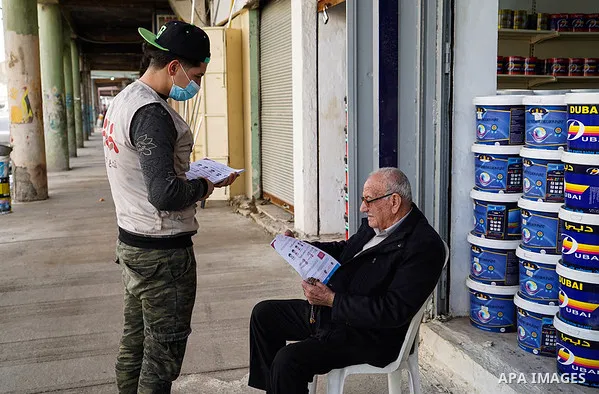 Iraqis look on the posters during awareness campaign about the coronavirus disease (COVID-19) in the northern Iraqi city of Mosul, on February 26. 2020. Photo by Ismail Adnan