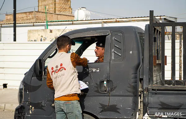 Iraqis look on the posters during awareness campaign about the coronavirus disease (COVID-19) in the northern Iraqi city of Mosul, on February 26. 2020. Photo by Ismail Adnan