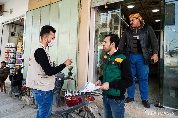 Iraqis look on the posters during awareness campaign about the coronavirus disease (COVID-19) in the northern Iraqi city of Mosul, on February 26. 2020. Photo by Ismail Adnan