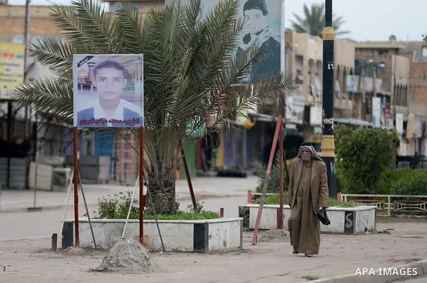 Iraqis walk past shops that are shuttered to help prevent the spread of the coronavirus, in Baghdad, Iraq, on March 21, 2020. Iraq announced a weeklong curfew to help fight the COVID-19 pandemic. Photo by Hassani Al-Asad...