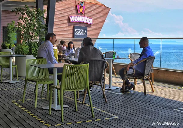 Turks, some wearing masks as a precaution against the spread of the coronavirus disease (COVID-19), sit in cafes, after the decision to open restaurants, cafes, cafeterias and public places in Istanbul, Turkey on June 3,...