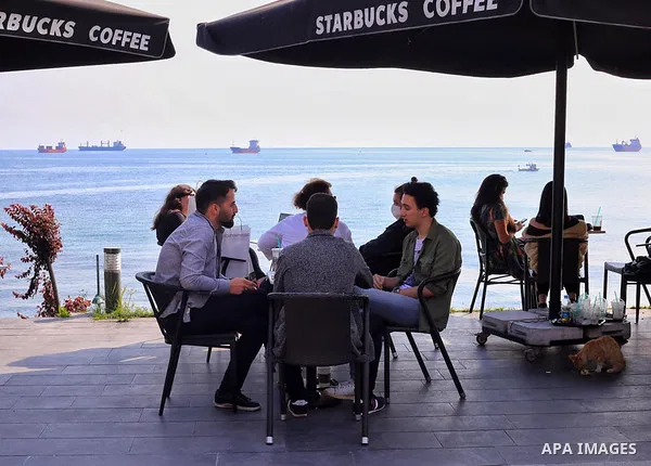 Turks, some wearing masks as a precaution against the spread of the coronavirus disease (COVID-19), sit in cafes, after the decision to open restaurants, cafes, cafeterias and public places in Istanbul, Turkey on June 3,...